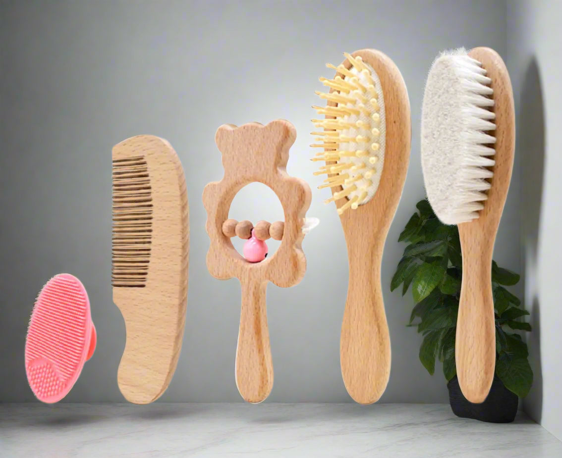 Set of wooden baby grooming tools including a comb, brush, and mirror on a white background.