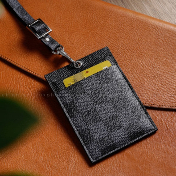 Black leather cardholder with a yellow card on a brown leather surface