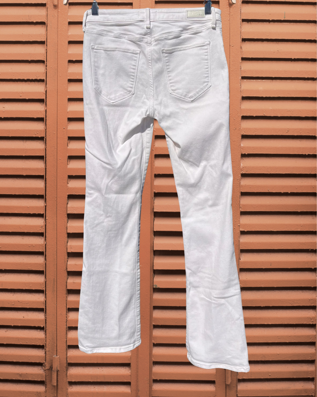 White jeans hanging against a wooden slatted background