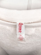Close-up of a white ribbed sweatshirt neck label with red text reading 'OshKosh' and smaller size information below, set against the white fabric.