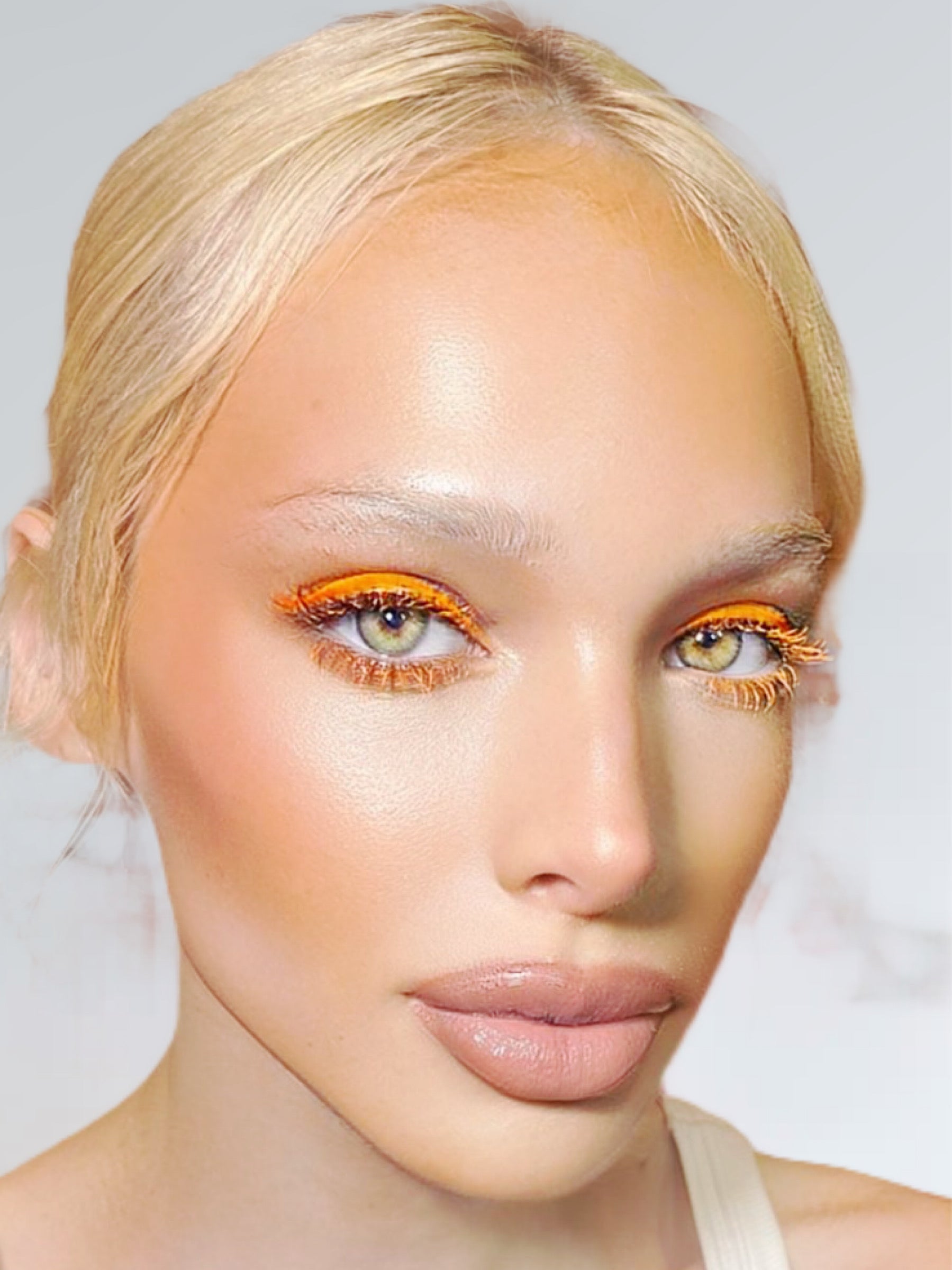 Close-up of a person with bright orange eyeshadow on a neutral background