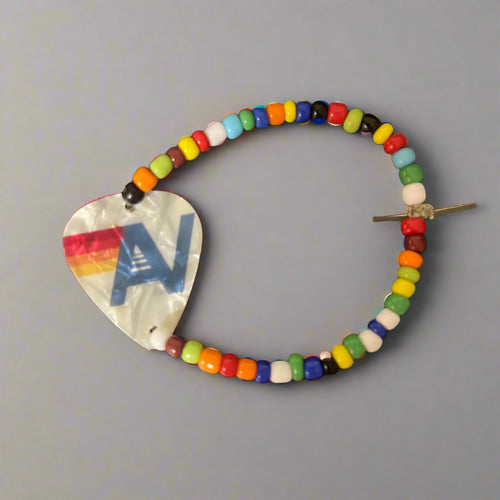 Colorful beaded hair clip with a heart-shaped metal piece on a gray background
