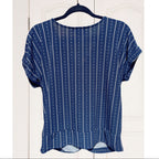Blue patterned top on a hanger against a white wooden background