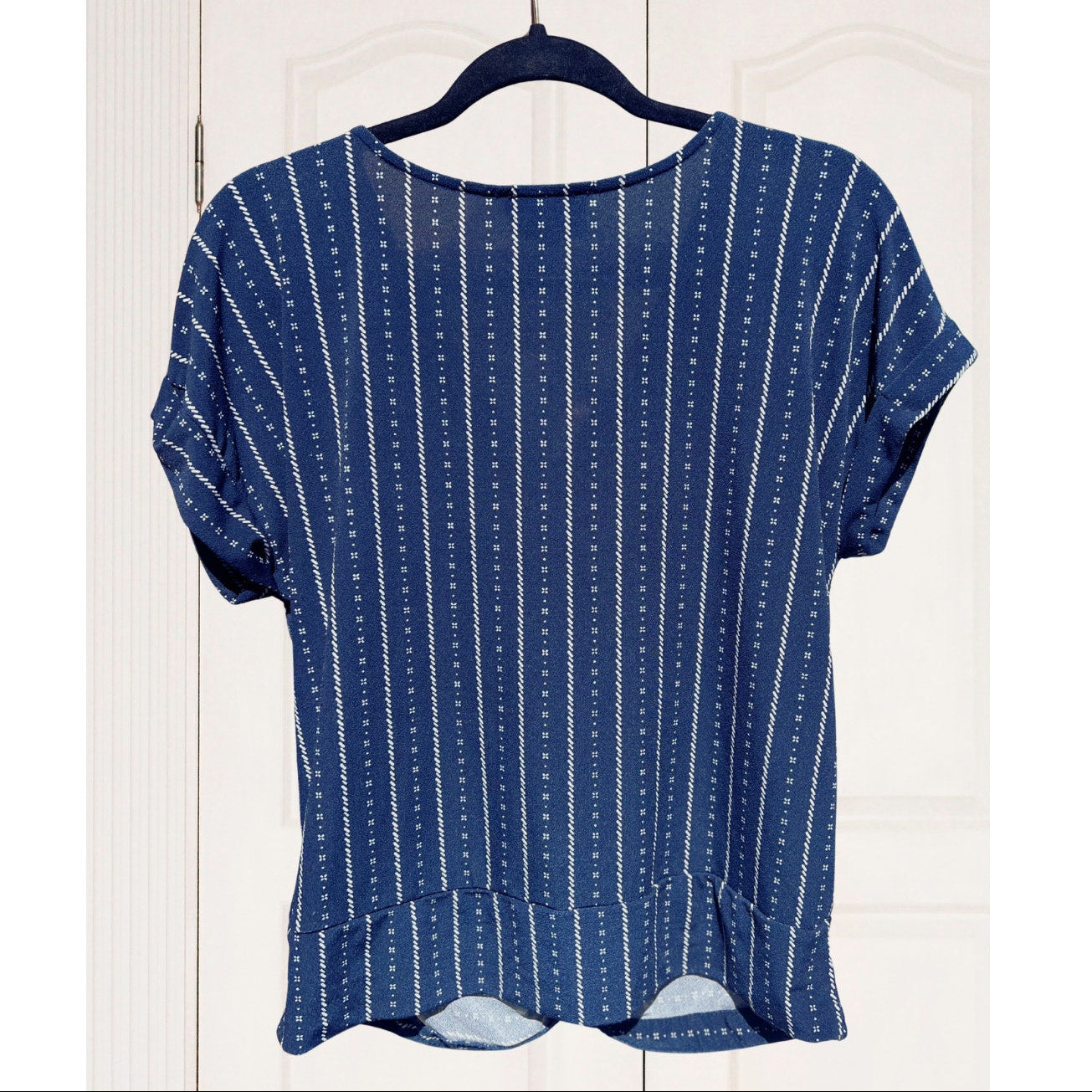 Blue patterned top on a hanger against a white wooden background