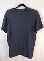 A dark charcoal gray short-sleeve t-shirt hanging on a black hanger against a white fabric backdrop.
