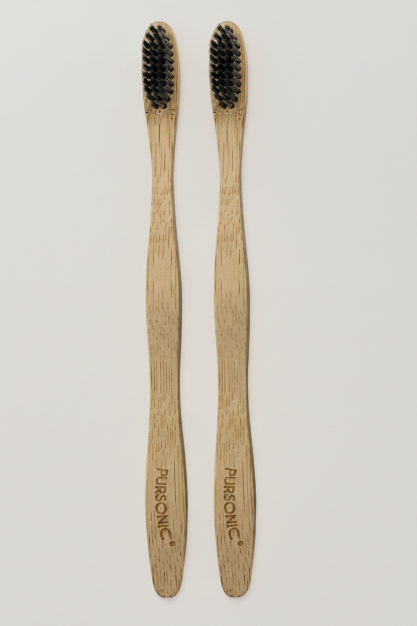 Two wooden toothbrushes with black bristles on a light beige marble background.