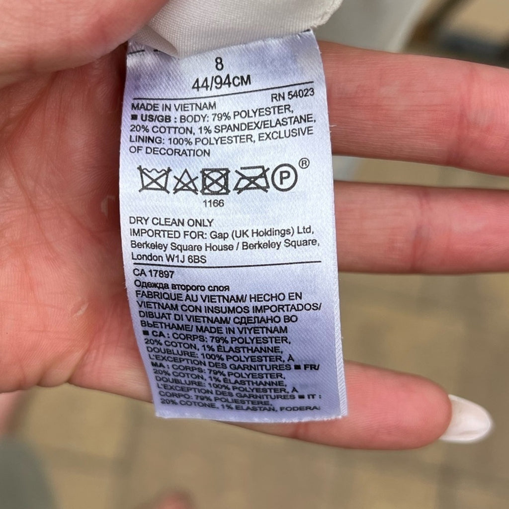 Clothing label held by a hand with a blurred background