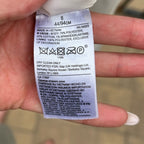 Clothing label held by a hand with a blurred background