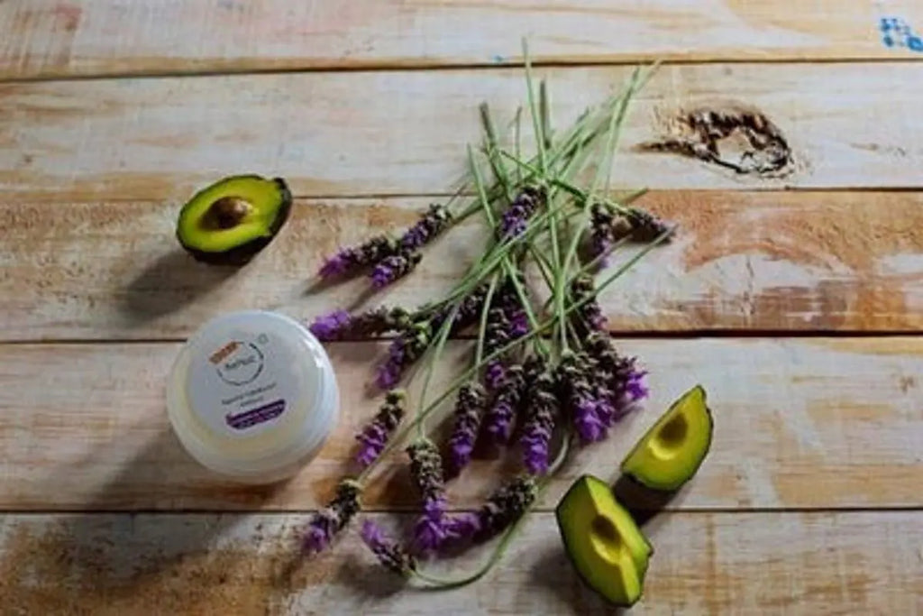 Jar of cream, avocado halves, and lavender on a wooden surface