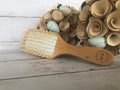Wooden hairbrush with natural bristles on a wooden surface with decorative eggs and flowers.