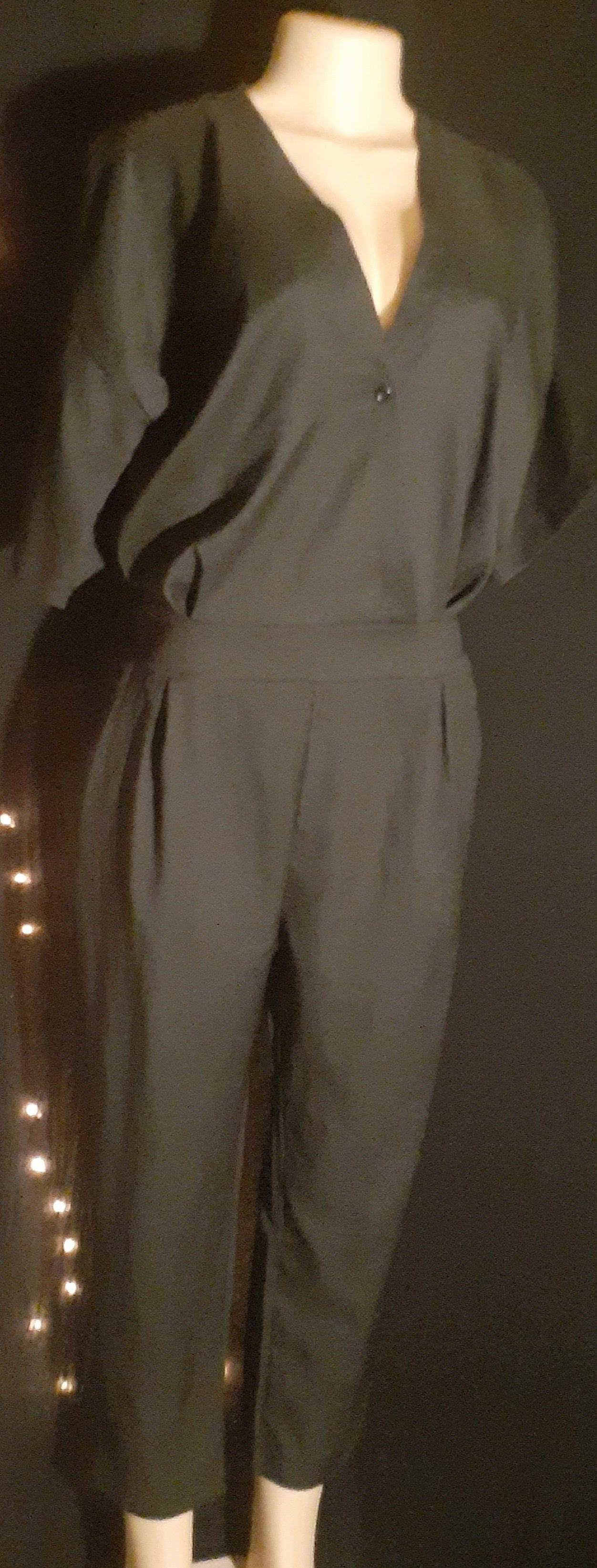 Black jumpsuit on a mannequin against a dark background