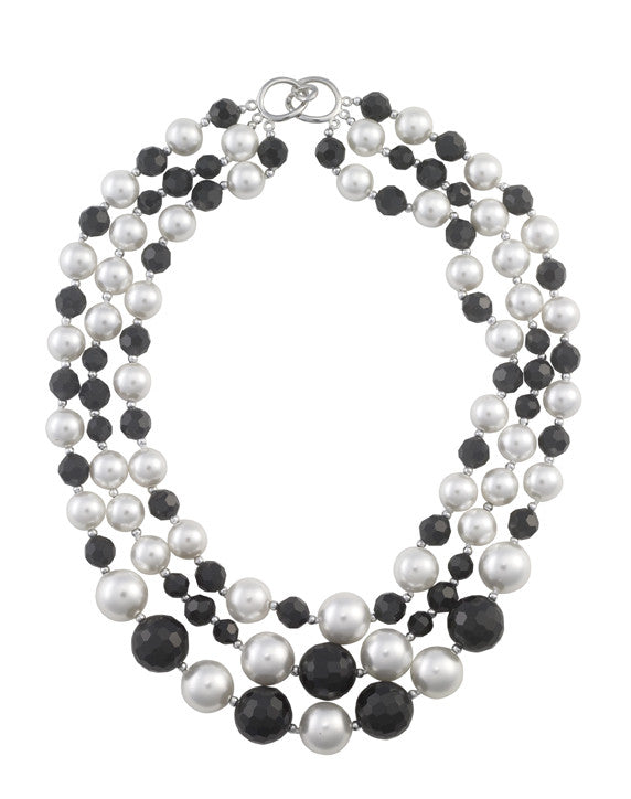 Multi-strand necklace with black and white beads on a white background