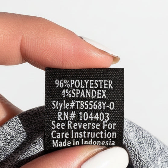 Hand holding a fabric label with text against a concrete surface
