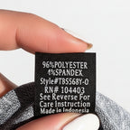 Hand holding a fabric label with text against a concrete surface