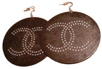 Pair of earrings with 'π' symbol design on a brown surface