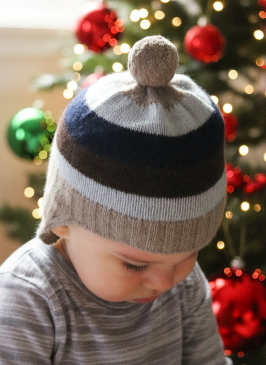 Child wearing a striped knit hat with a pom-pom on a holiday background