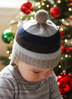 Child wearing a striped knit hat with a pom-pom on a holiday background