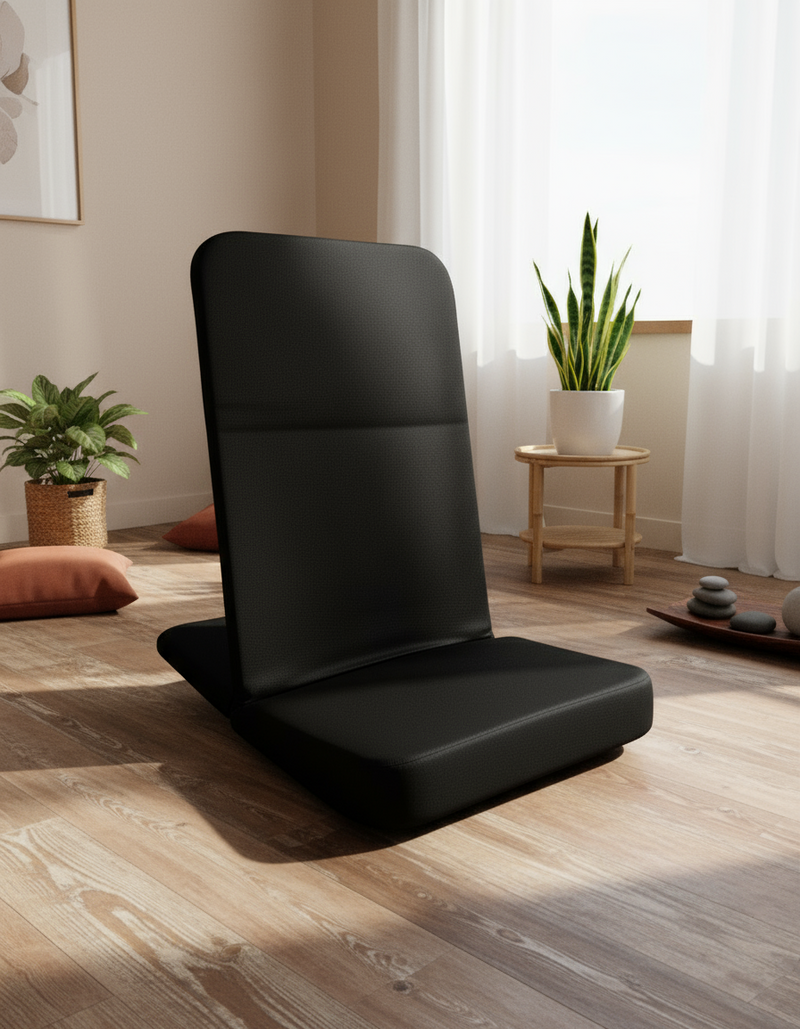 Black floor pillow in a room with plants and a wooden table.