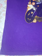 A close-up of a purple t-shirt featuring a graphic print of a motorcycle with flames on the upper right side.