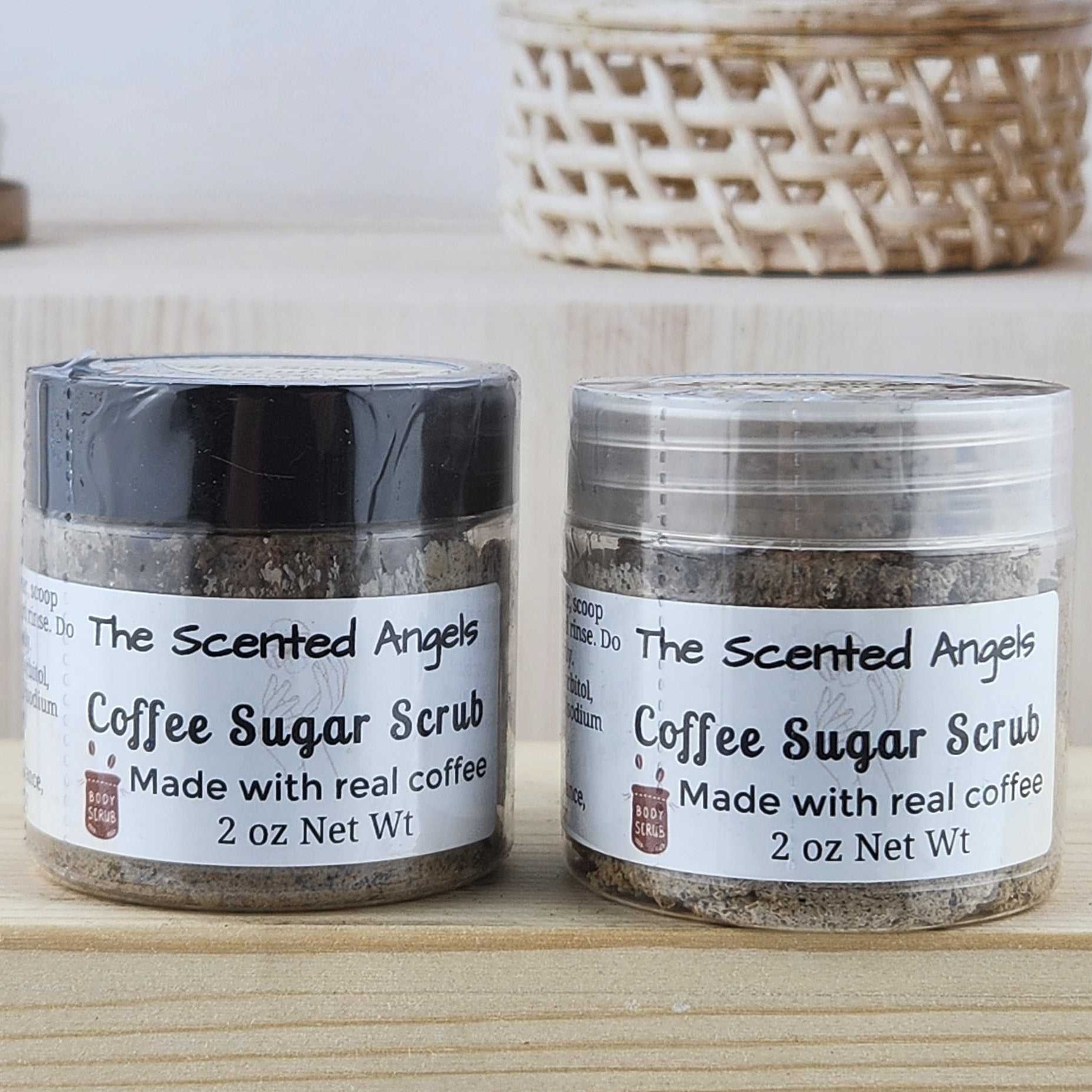 Two jars of coffee sugar scrub on a wooden surface with a neutral background.