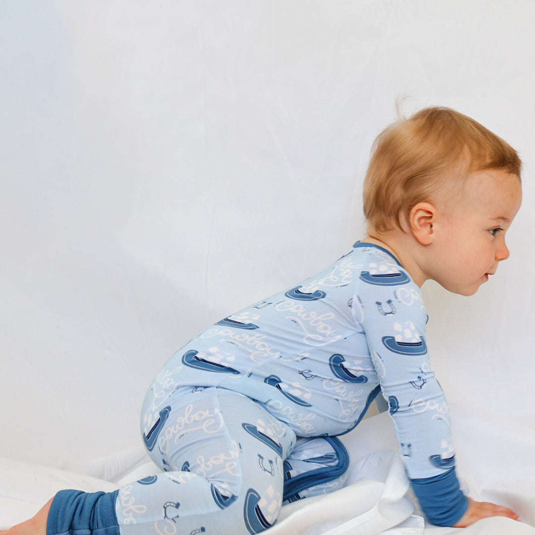 Baby in blue pajamas with cowboy pattern on a white background