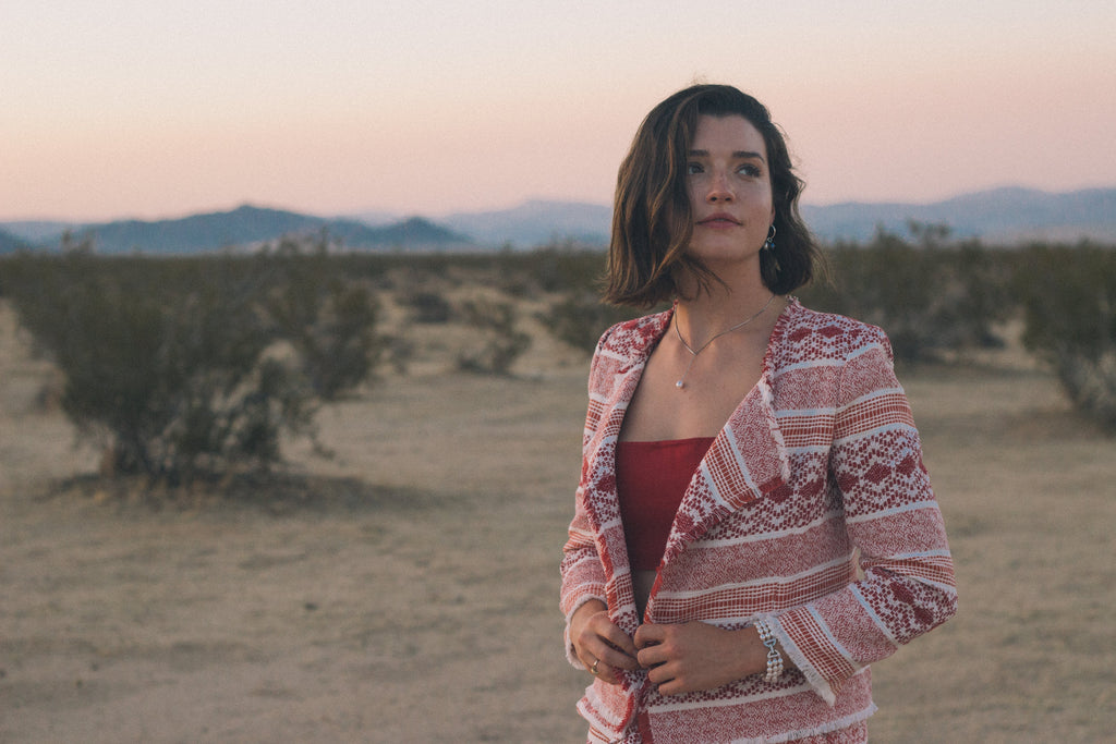 Woman standing in a desert landscape with mountains in the background
