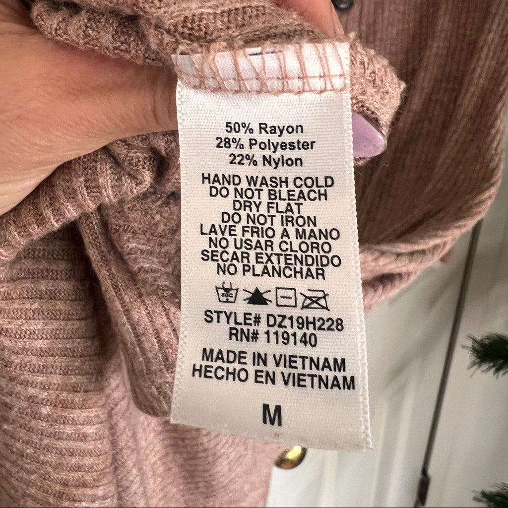 Clothing label on a pink sweater with text and symbols.