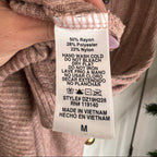 Clothing label on a pink sweater with text and symbols.
