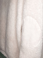 Close-up of a soft off-white fleece or sherpa fabric with a contrasting oval patch of ribbed corduroy texture.