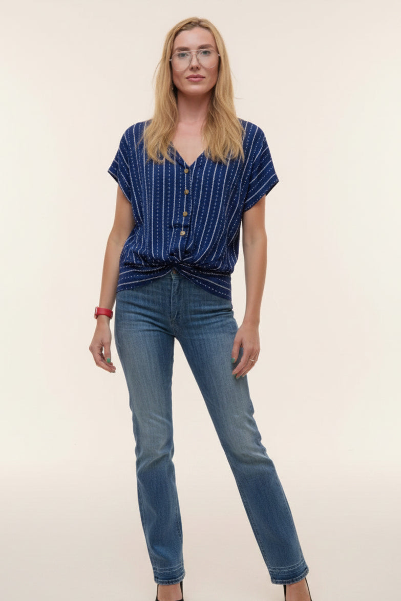 Woman wearing a blue striped shirt and jeans against a plain background