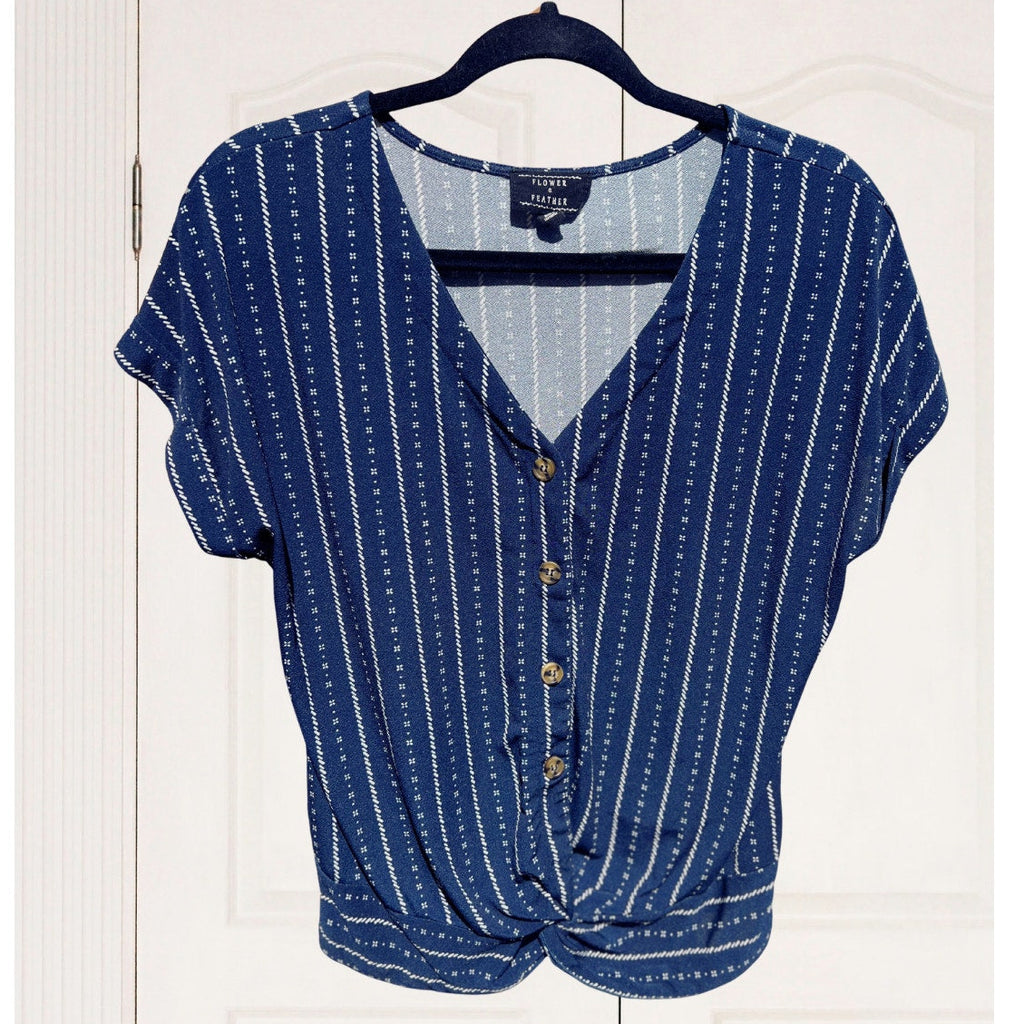 Blue patterned blouse on a hanger against a white wooden door background
