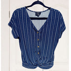 Blue patterned blouse on a hanger against a white wooden door background
