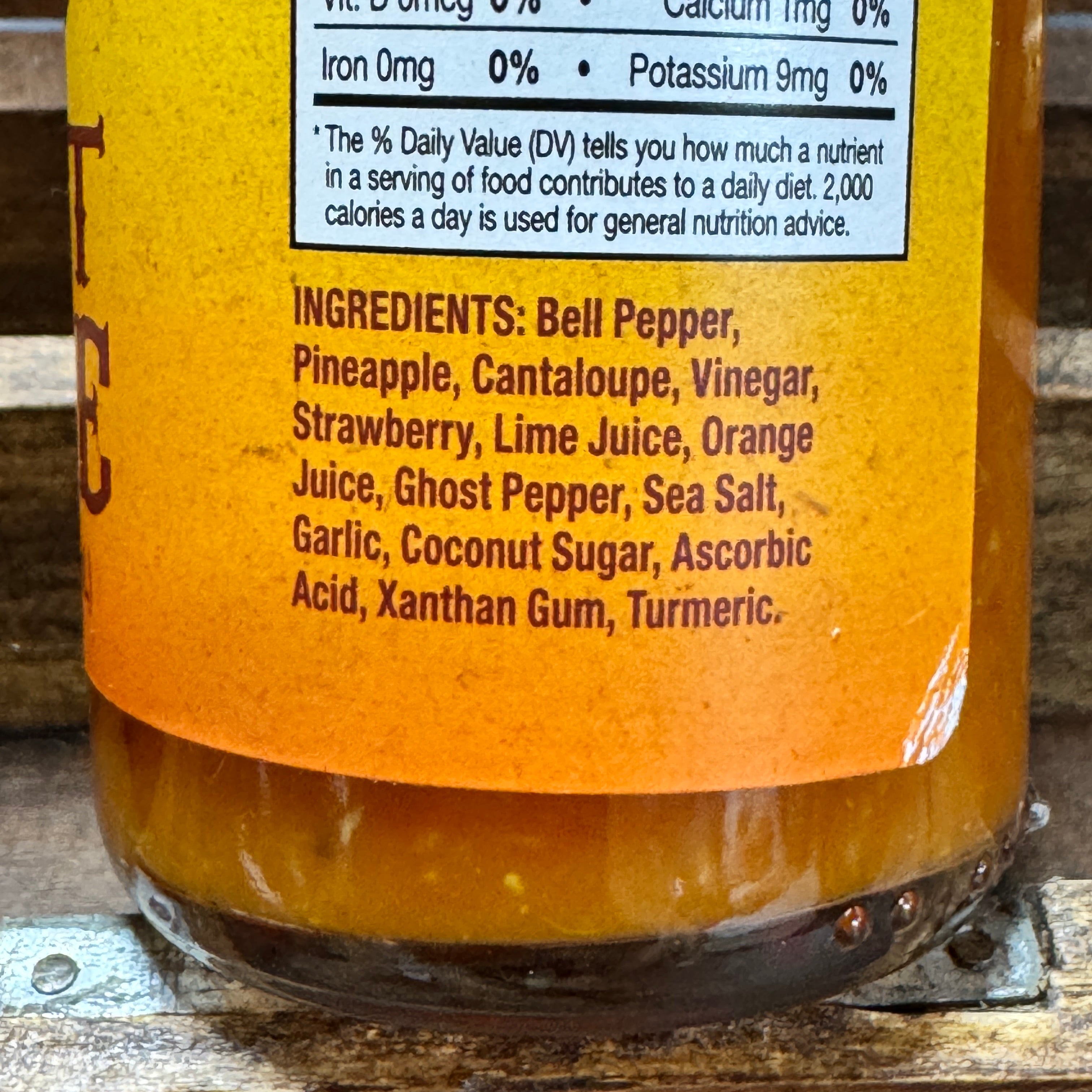 Close-up of a bottle label with ingredients listed on a wooden surface