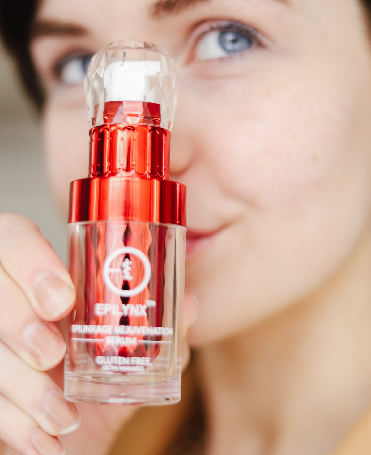 Red skincare serum bottle held by a person with a blurred background