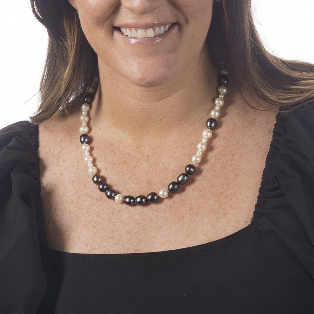Woman wearing a black and white beaded necklace against a plain background