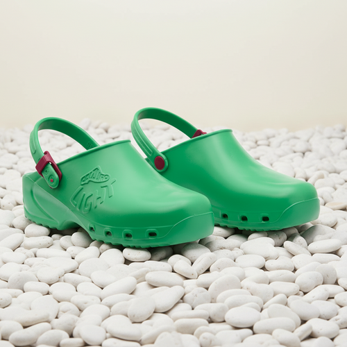 Pair of green clogs with red straps on a white background