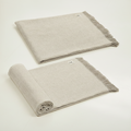 Two beige woven blankets, one folded and one draped, on a white background