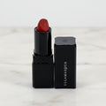 Red lipstick with black casing on a white background, featuring the Illamasqua brand.