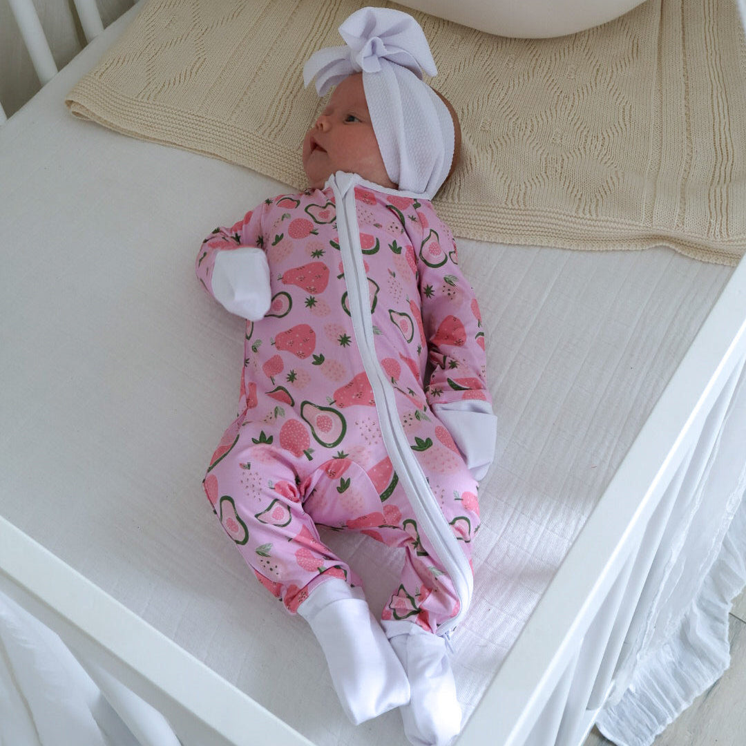 Baby in pink outfit with white bunny ears lying in a crib.