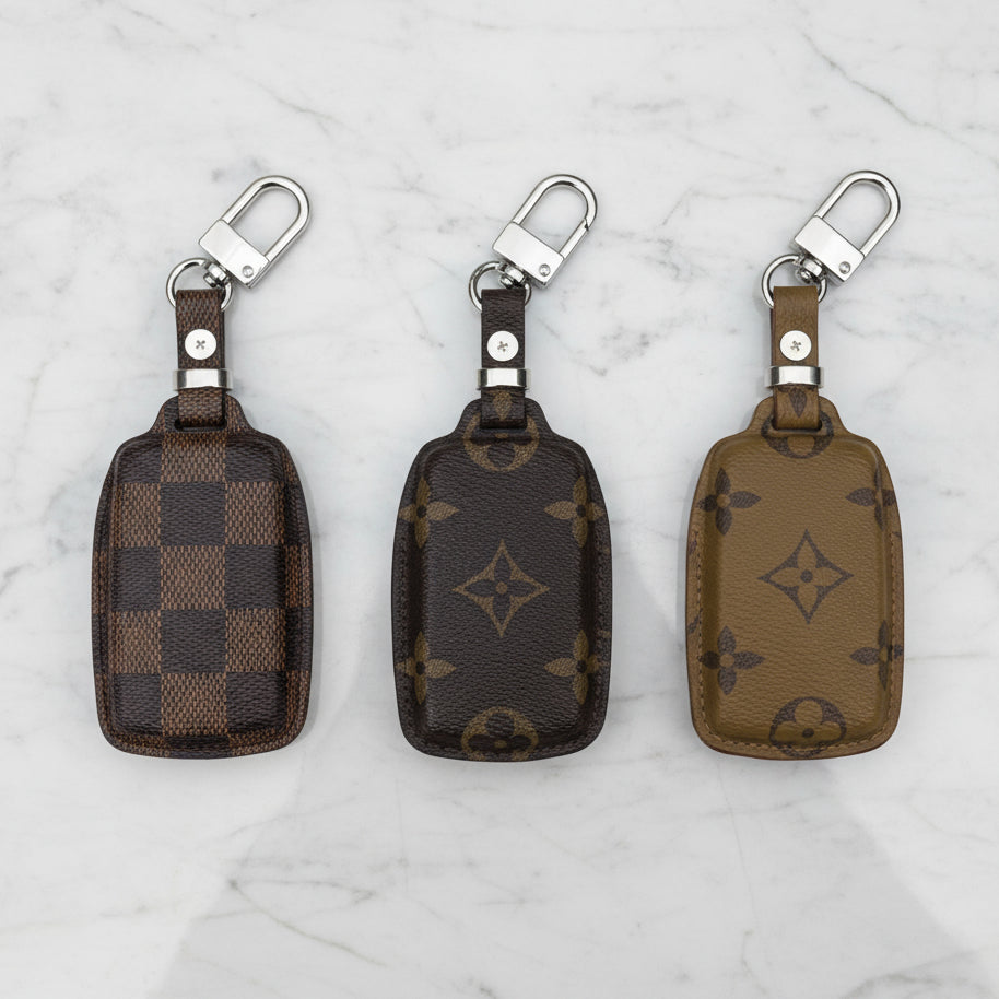 Three Louis Vuitton keychains on a marble surface
