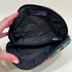 Black pouch with 'Indie Ella' label held by a hand on a textured surface