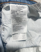 Close-up of the interior label and waistband of a pair of blue denim jeans, showing printed care instructions and brand text in multiple languages.