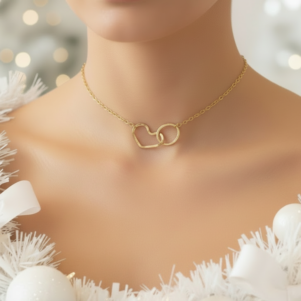 Gold necklace with interlocking heart pendants on a mannequin against a white decorative background