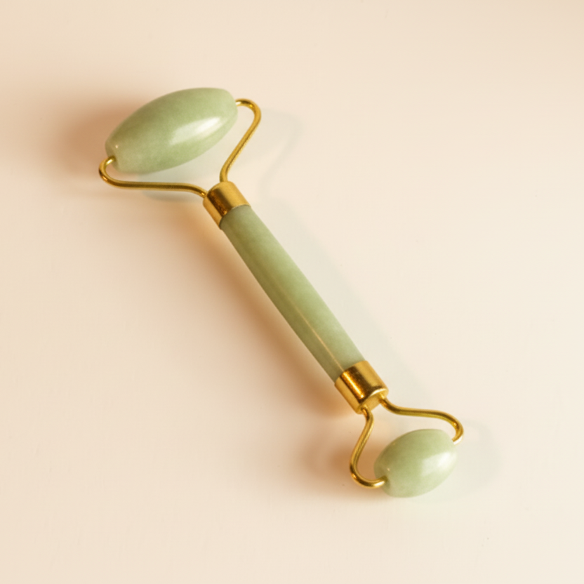 Green jade roller on a beige background