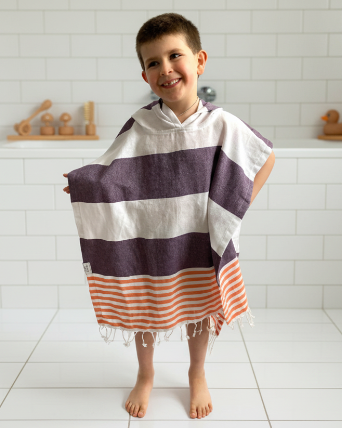 Child wearing a striped towel in a bathroom