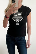 Person wearing a black t-shirt with a logo in a home setting