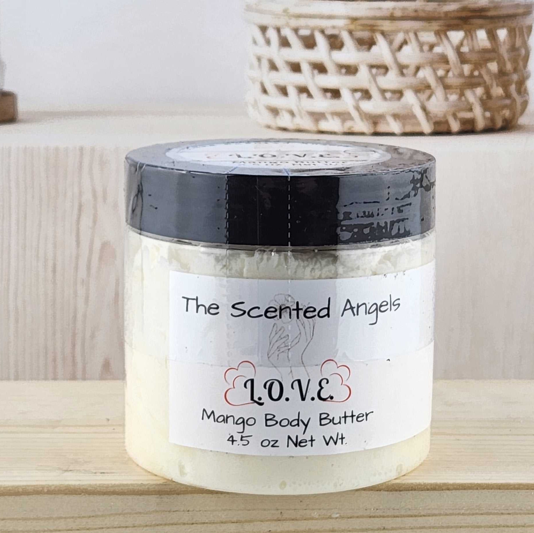 Jar of mango body butter labeled 'The Scented Angel' on a wooden surface.