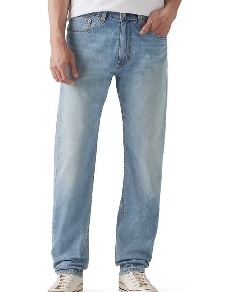 A person wearing light-wash blue denim jeans with a white t-shirt and white sneakers, shown from the waist down against a plain white background.