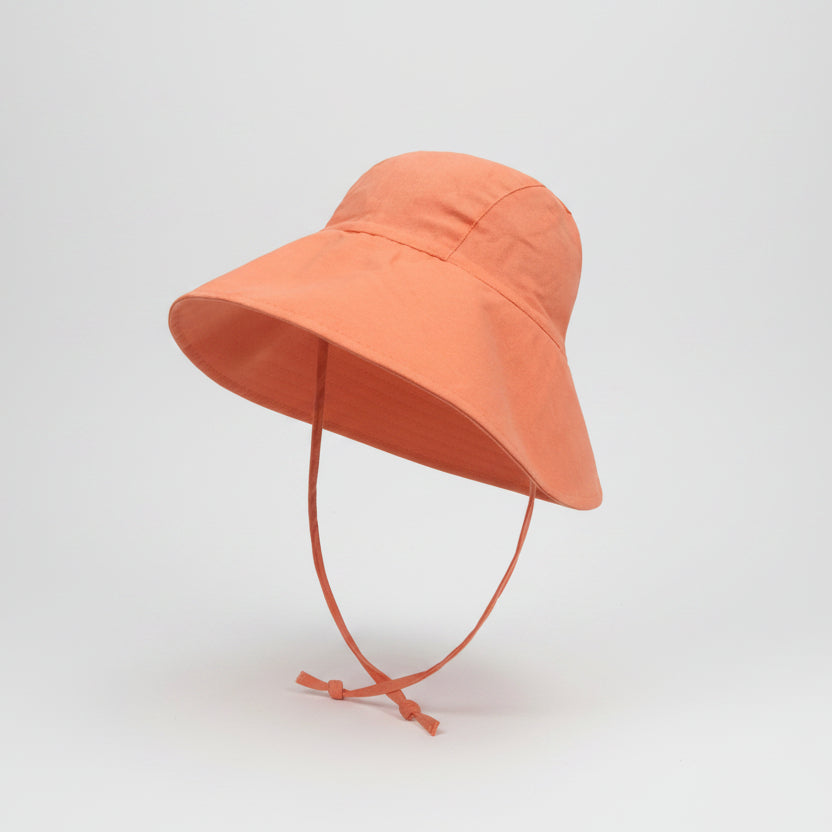 Orange bucket hat with a tie on a white background