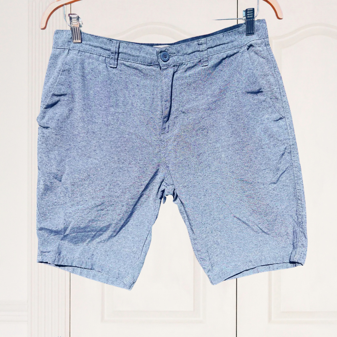 Blue shorts hanging on a white background with a brand logo at the bottom left corner.